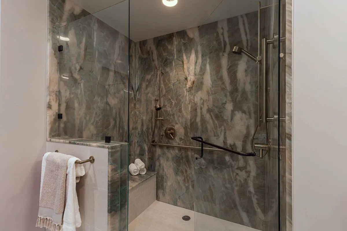 Curbless glass shower with green marble-look tile and a grab bar, North York