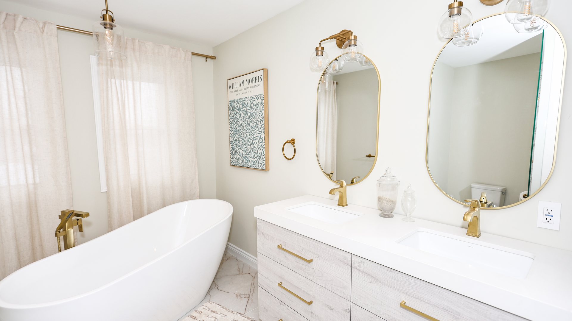 Freestanding tub and a double vanity with brushed gold faucets and oval mirrors, Thornhill ensuite