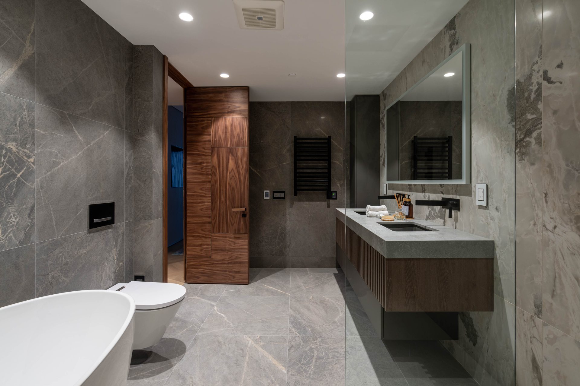 Stone-wrapped ensuite with floating double vanity and walnut door from a bathroom renovation in Toronto