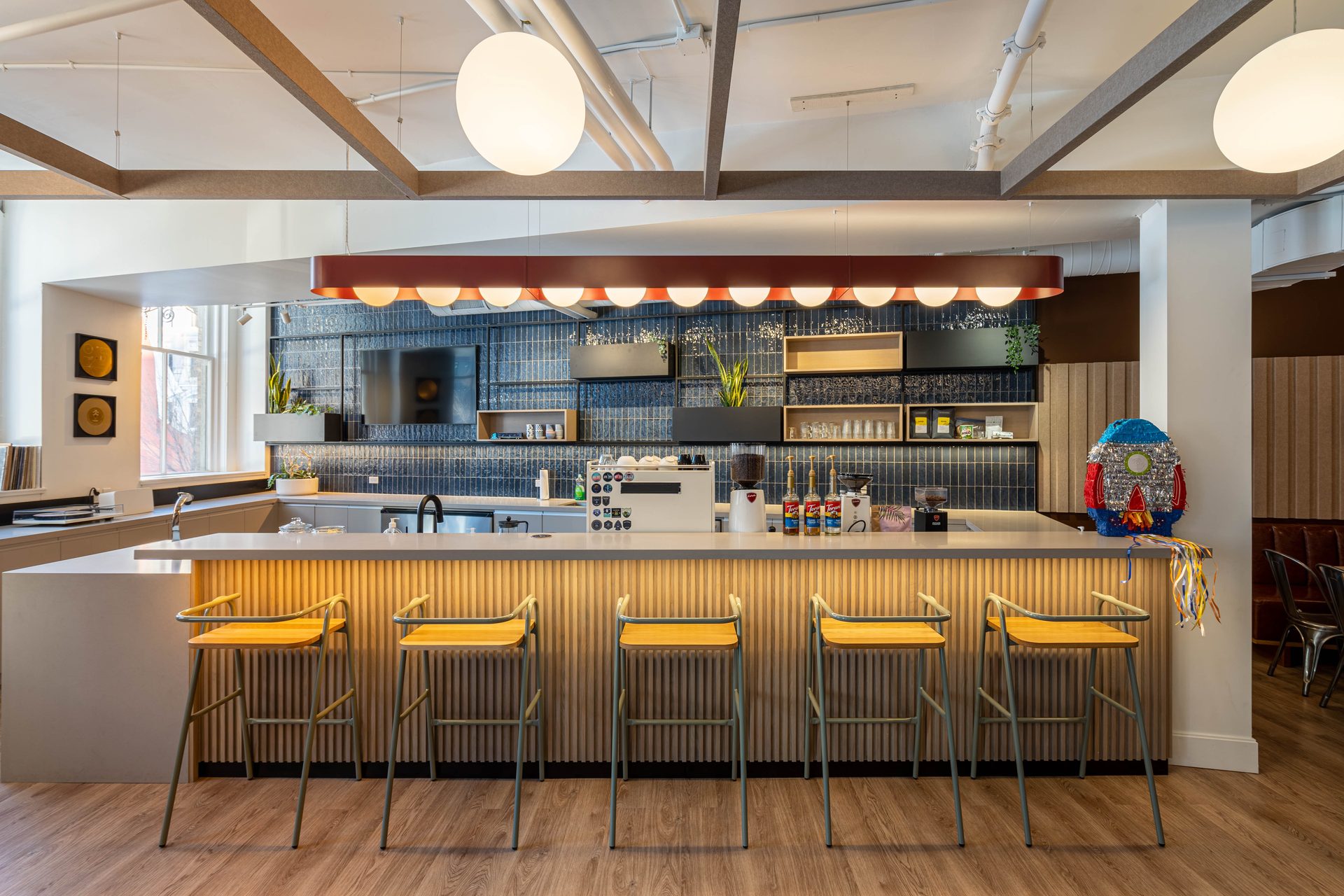 Commercial office kitchen and coffee bar with orange pendant lighting and navy tile backsplash, Toronto