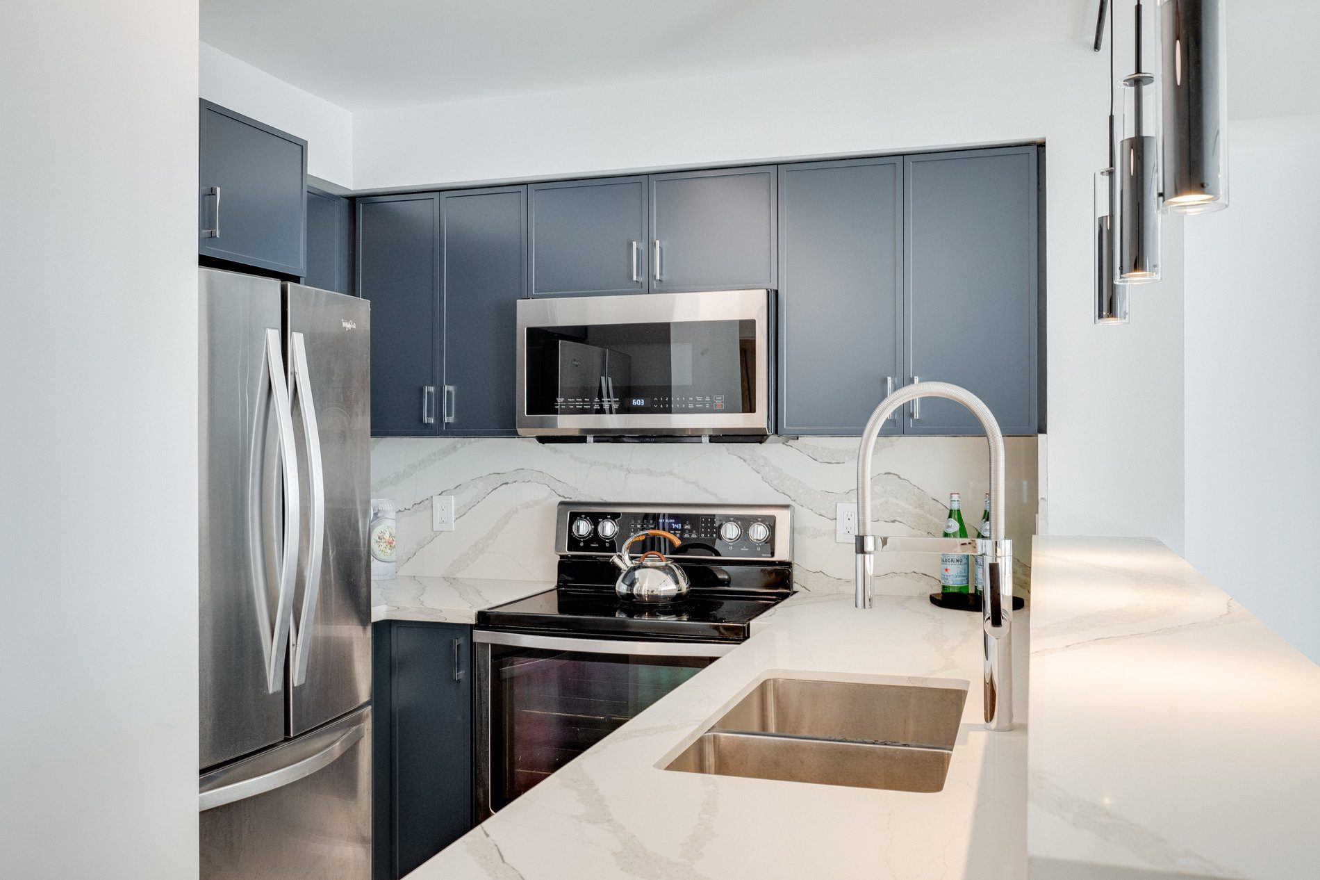 Renovated condo kitchen with navy cabinets and quartz counters in Etobicoke