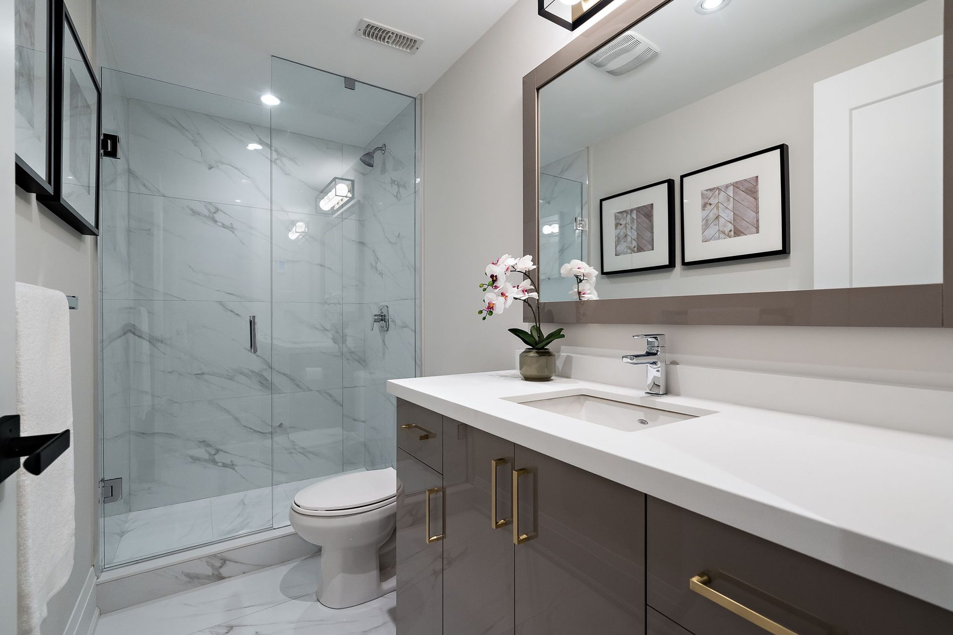 Glass walk-in shower in marble-look porcelain beside a taupe vanity with brushed gold pulls, Etobicoke