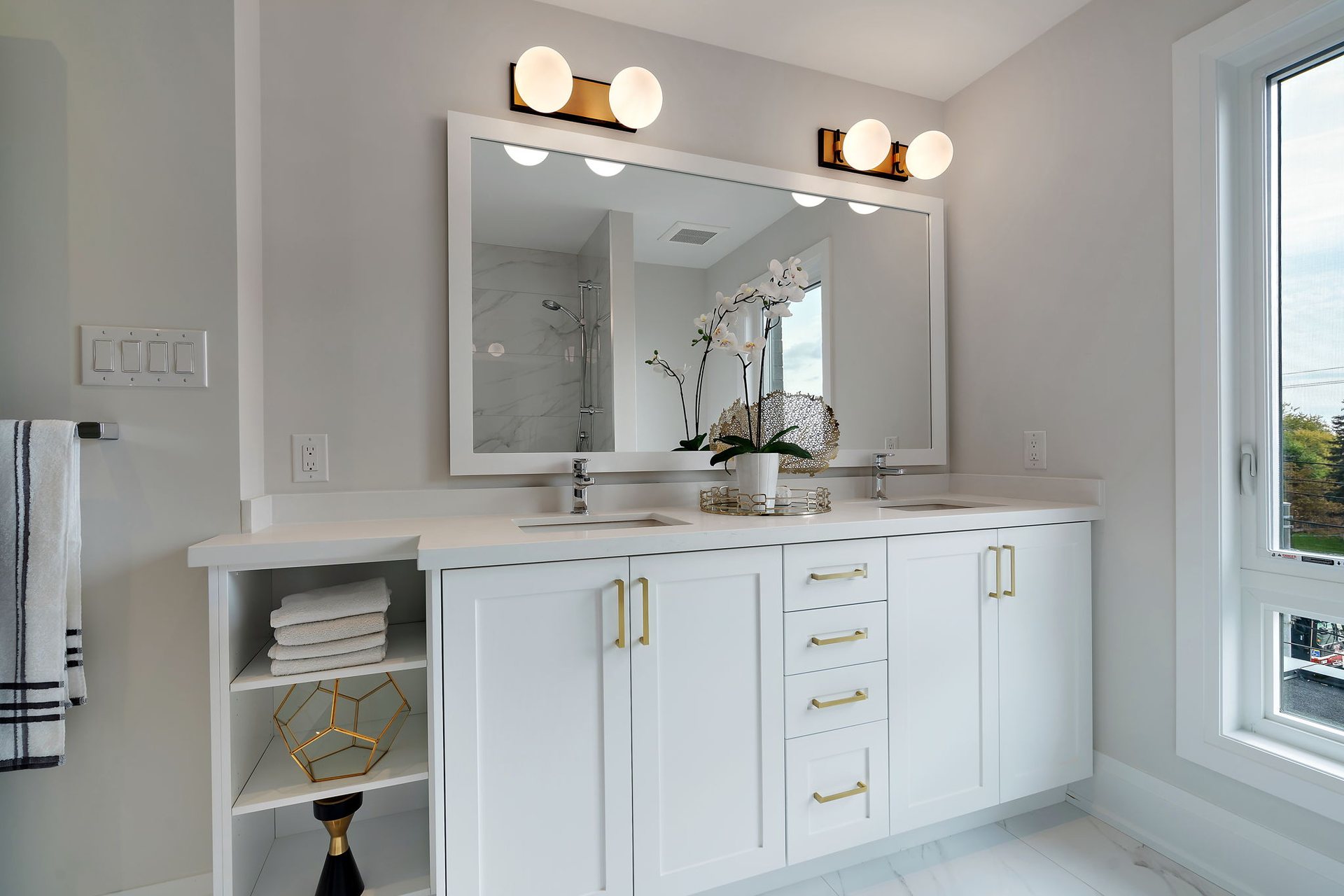 White double vanity with open towel shelving, gold globe sconces and brushed gold pulls, Etobicoke