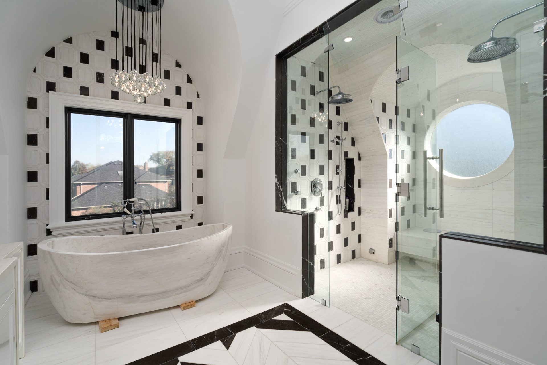 Marble freestanding tub under a crystal chandelier beside a glass steam shower, custom home in Thornhill