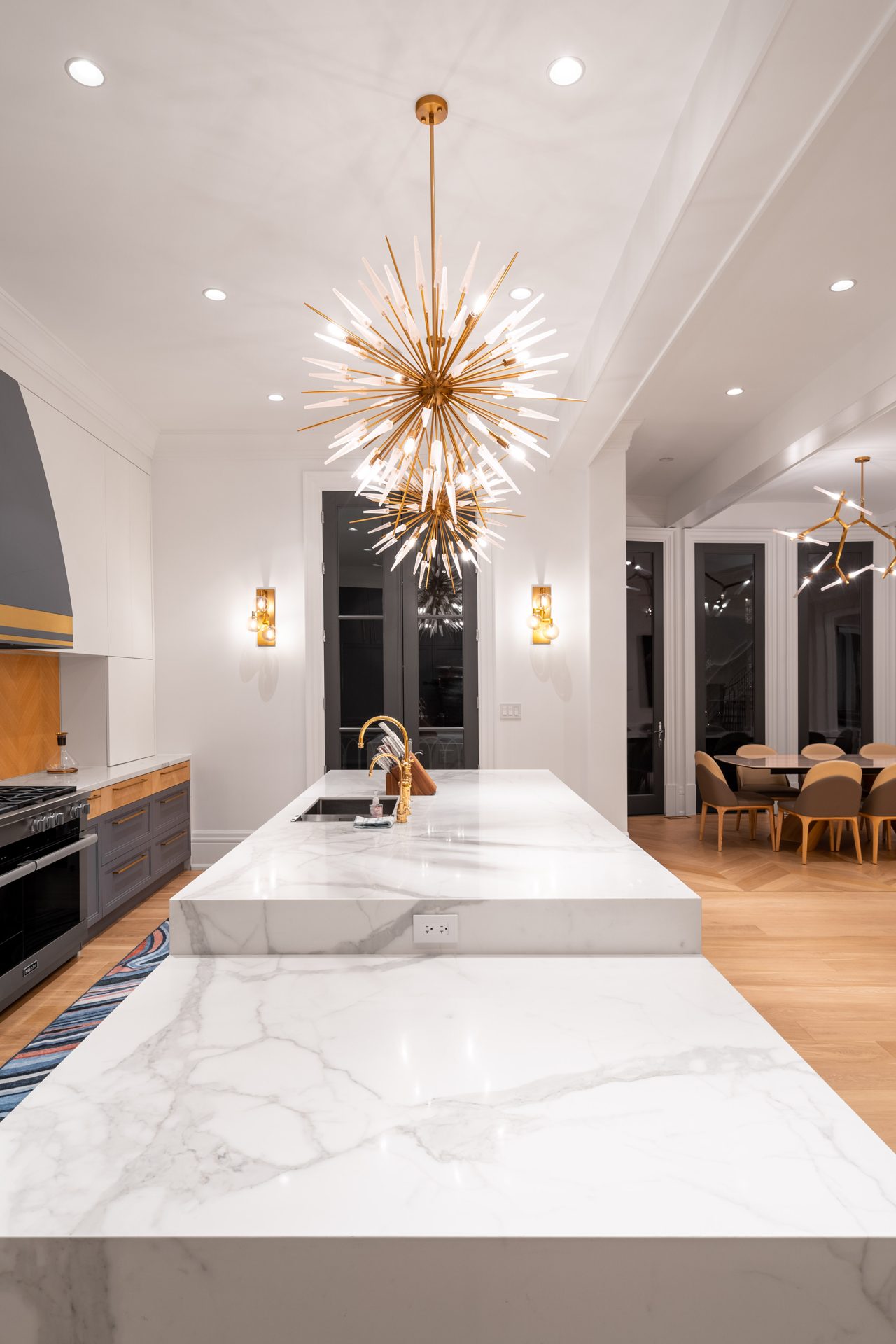 Stepped marble waterfall island under a brass starburst chandelier, Thornhill