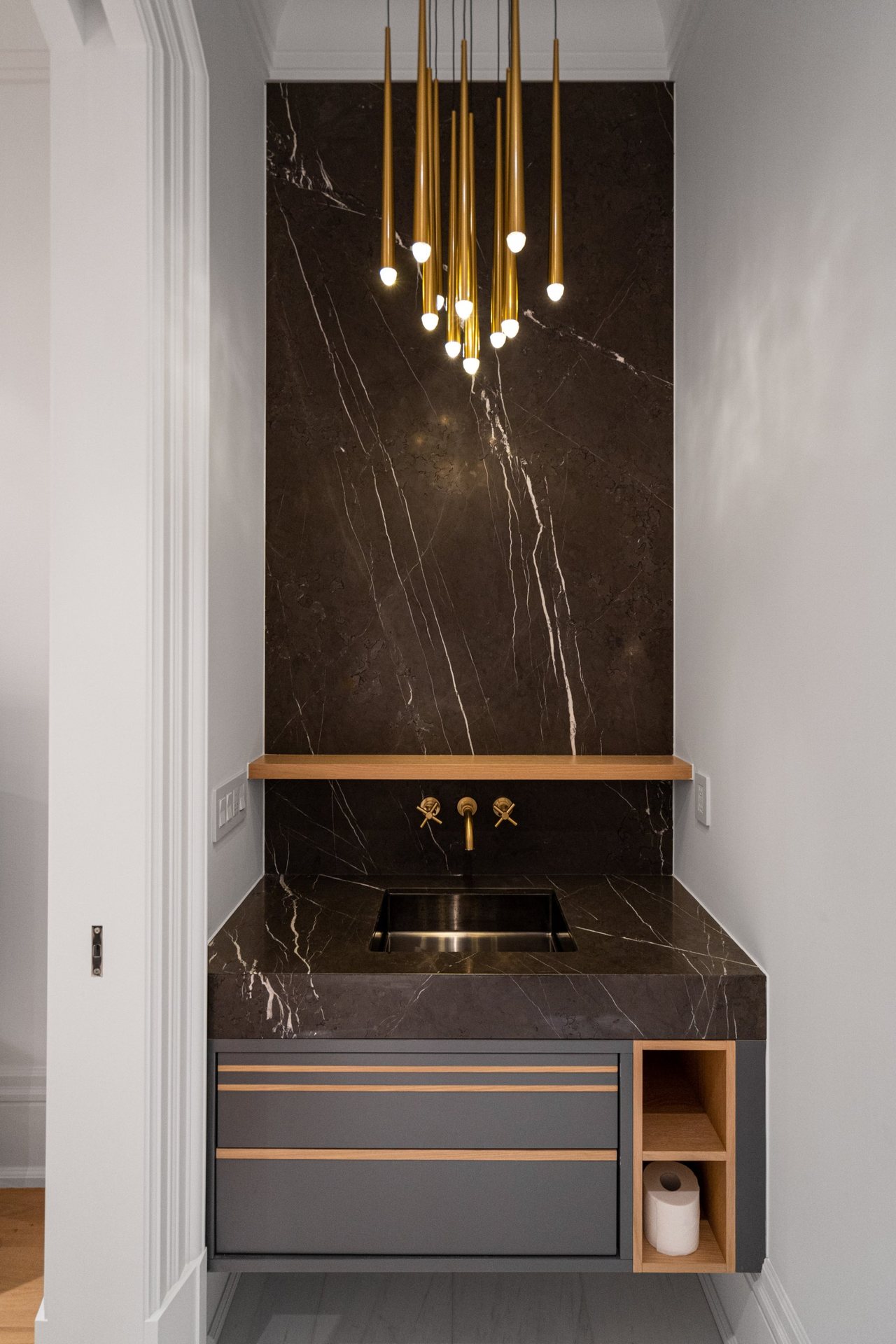 Black marble powder room with a brass pendant cluster, a wall faucet and a floating oak trimmed vanity, Thornhill