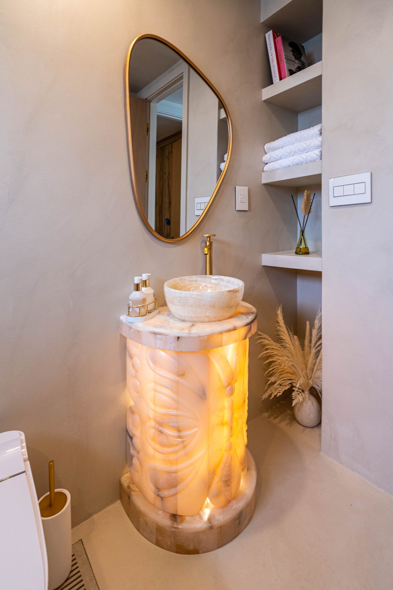 Backlit onyx pedestal sink with a brass faucet and built-in shelving, Richmond Hill