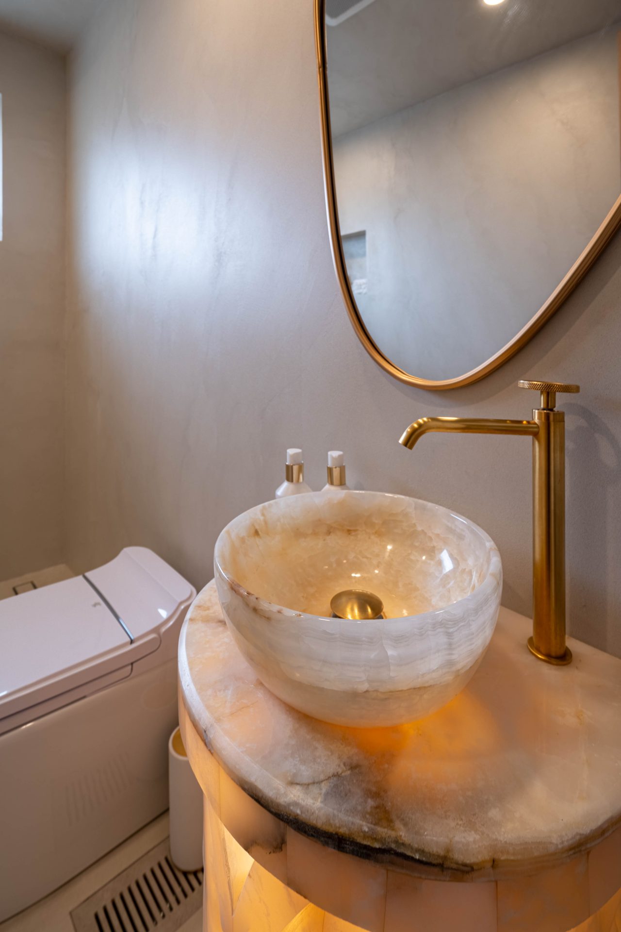 Onyx vessel sink with a brushed brass faucet and an oval mirror, Richmond Hill